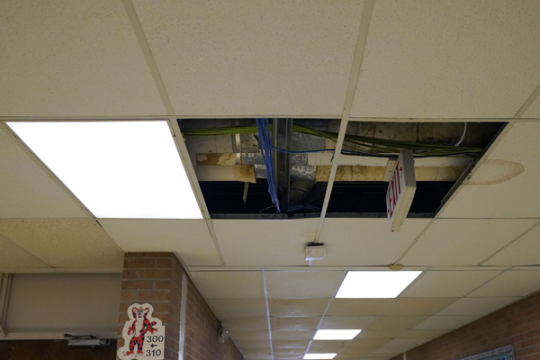 A damaged and duct-taped ventilation system can be seen through a hole in an elementary school's ceiling. 