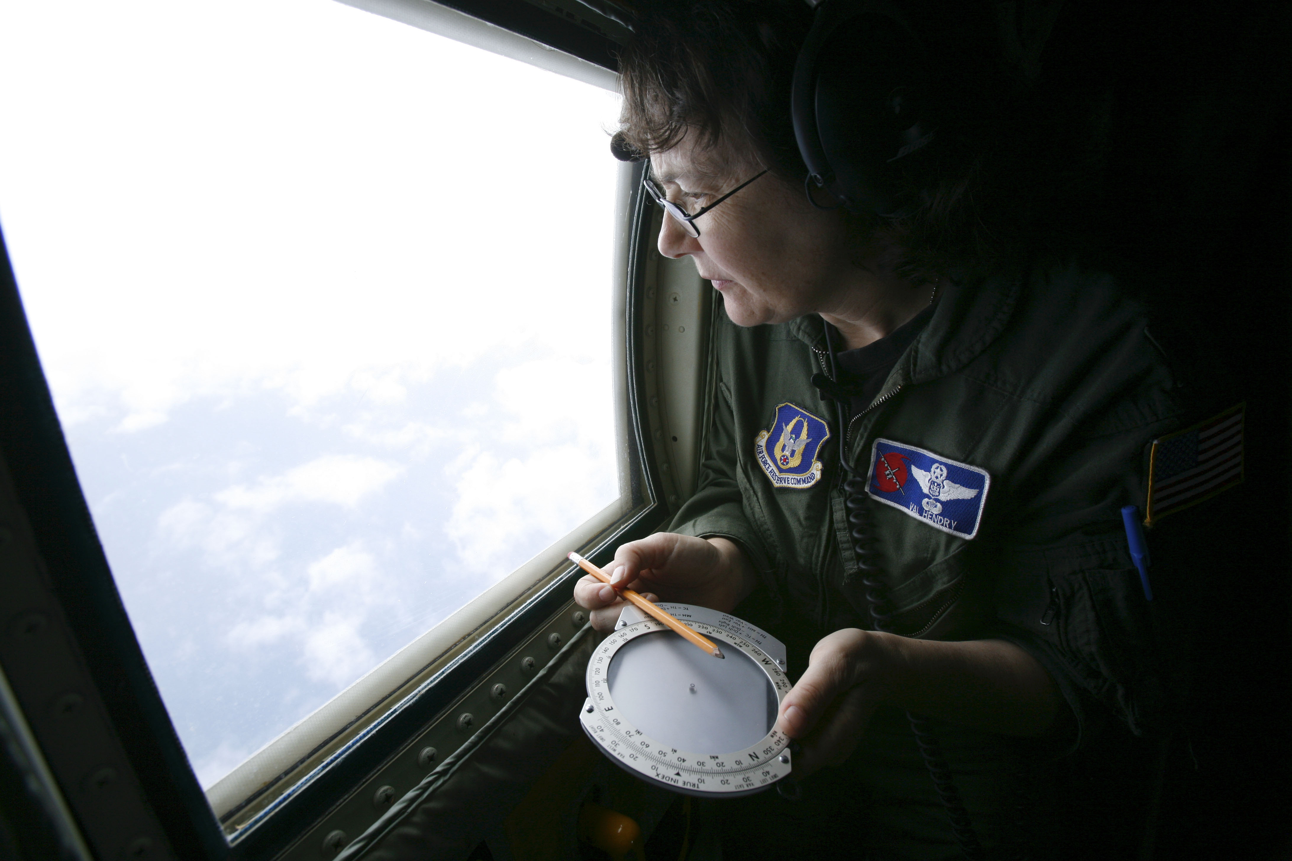 Weather officer Lt. Col. Valerie Hendry uses a rudimentary compass to gauge the direction of winds churning the ocean aboard a Hurricane Hunter plane above Tropical Storm Gustav in 2008.